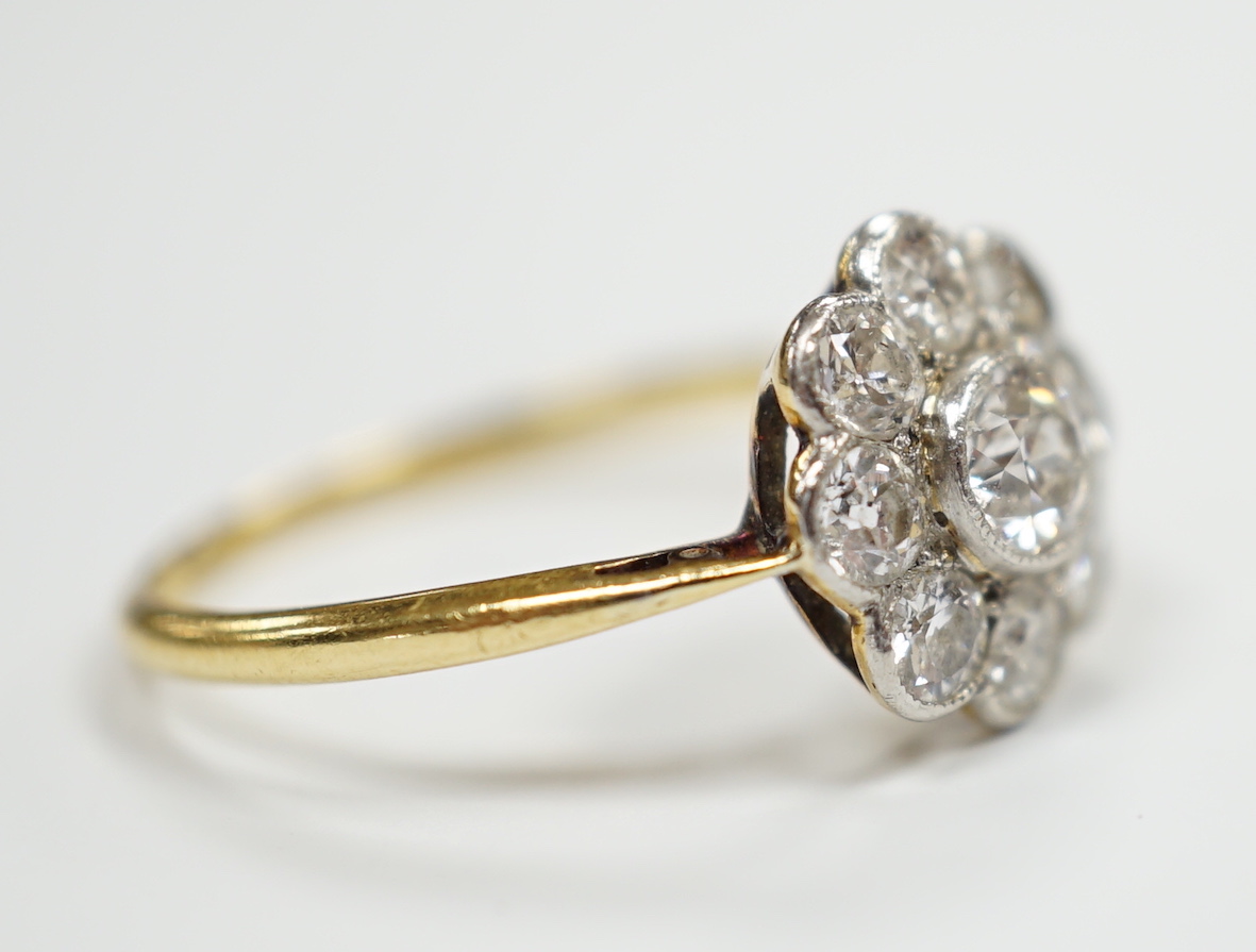 A 1930's/1940's 18ct and nine stone millegrain set diamond set flower head cluster ring, size P, gross weight 2.4 grams.